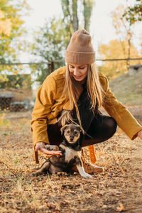 Woman volunteer meeting homeless dog puppies in fall nature background. pet love, caring for a pet 