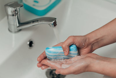 Cropped hand washing hands in sink