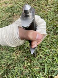 Close-up of hand holding sword on grass