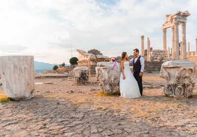 Bride and groom romancing while standing at old ruin