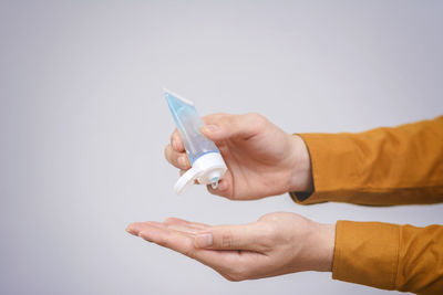 Close-up of hand holding paper over white background