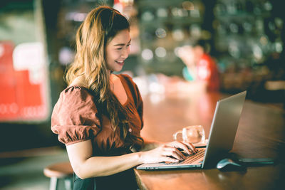 Young woman using mobile phone in laptop