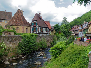 Houses by trees and buildings against sky