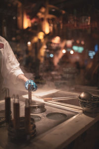 Cropped hand of chef cooking food on street at night