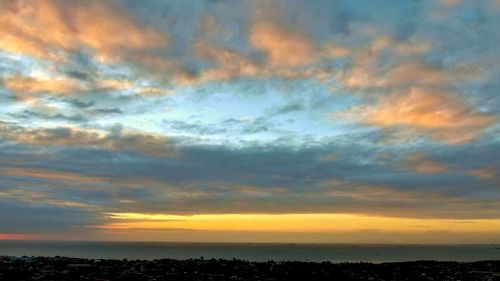 Scenic view of sea against dramatic sky during sunset
