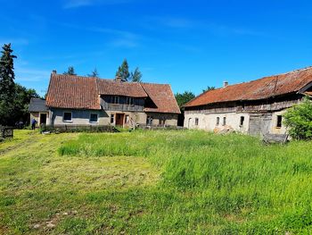 Houses on field by old building against sky