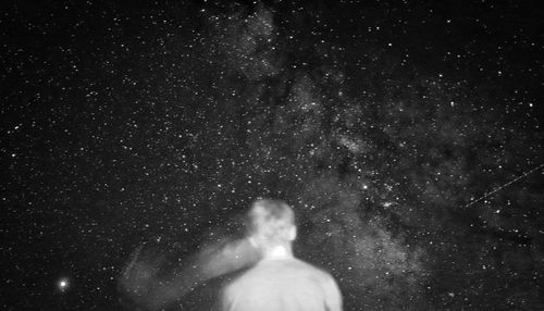 Rear view of woman against sky at night