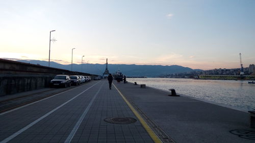 Vehicles on road against sky during sunset