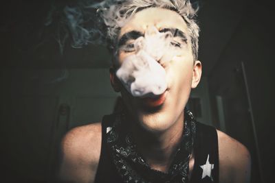 Portrait of young man blowing smoke