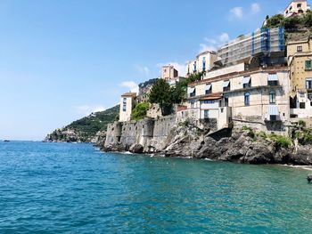 Buildings in sea against blue sky