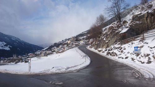 Snow covered road by mountains against sky