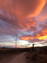 Silhouette of electricity pylons against dramatic sky