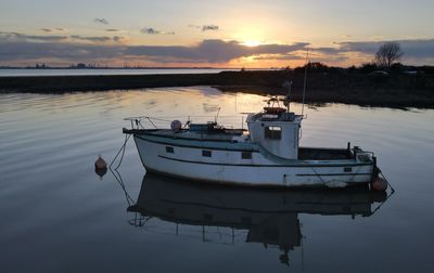 Boat moored in lake against sky during sunset