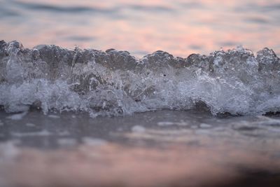 Close-up of sea waves against sky during sunset