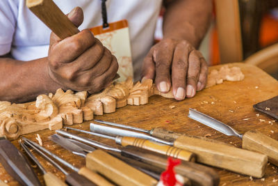 Midsection of man carving wood