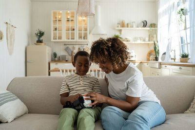 Mother and daughter sitting on sofa at home