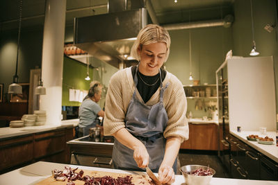 Smiling non-binary person chopping vegetables during cooking class in kitchen