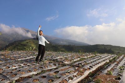 Rear view of man standing on mountain against sky