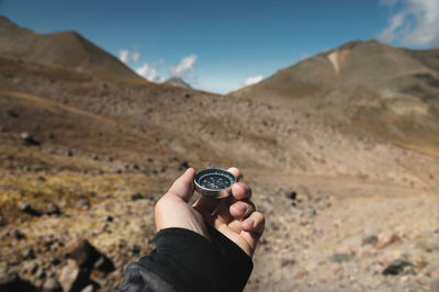 First-person view of a male traveler's hand holding a magnetic compass against the backdrop 