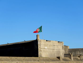 Low angle view of portugese flag against clear blue sky