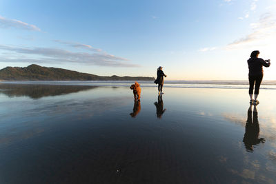 People standing on beach against sky