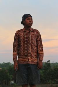 Young man standing against sky during sunset