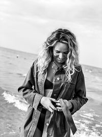 Young woman standing on beach against sky