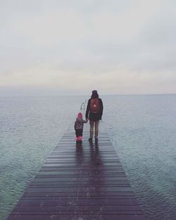 Rear view of man and child walking on beach