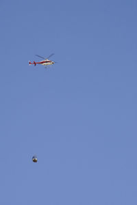 Low angle view of helicopter flying against clear blue sky