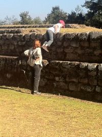 Full length of friends standing on stone against sky