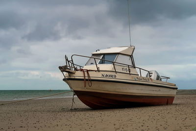 Boat moored on beach against sky