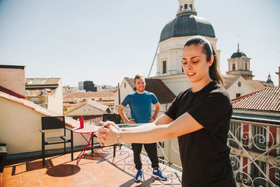 A couple doing training with rubber resistance band on their fooftop