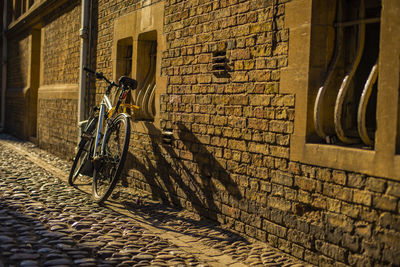 Bicycle parked on footpath against building