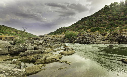Scenic view of river amidst rocks against sky