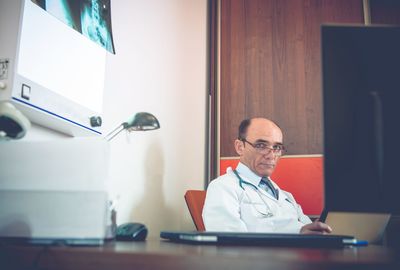 Portrait of doctor sitting at desk in hospital