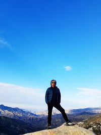 Portrait of man standing on mountain against blue sky