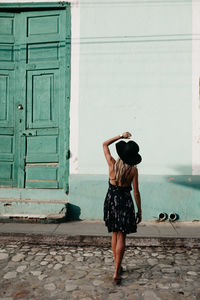 Rear view of woman standing against door of building