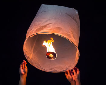 People releasing illuminated paper lantern into the air for it to rise up, lantern festival