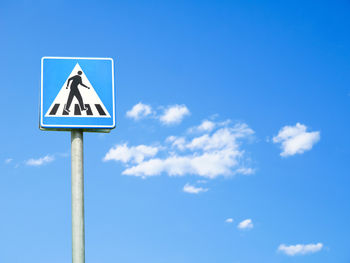 Low angle view of road sign against blue sky