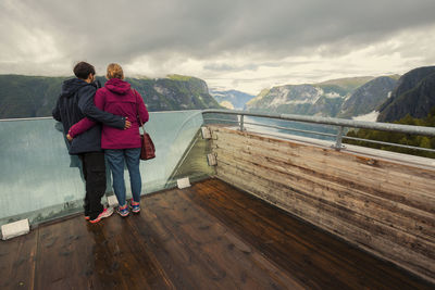 Rear view of people looking at mountain against sky