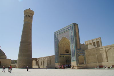 Group of people in front of historical building against clear sky