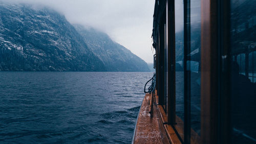 Boat sailing on sea by mountains