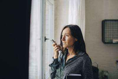 Portrait of woman standing against window