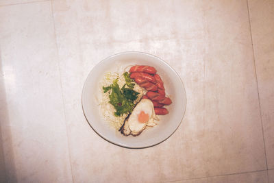 High angle view of fried egg and sausages in plate on floor