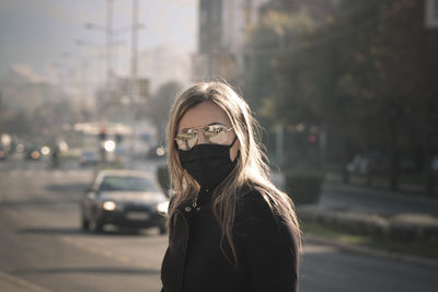 Portrait of young woman standing on street in city