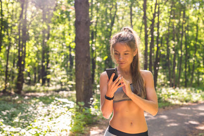 Young woman standing on mobile phone in forest