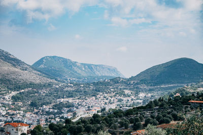 Aerial view of townscape and mountains against sky