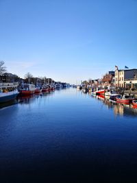 View of canal and buildings against clear blue sky