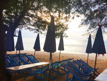 Chairs and tables on beach against sky