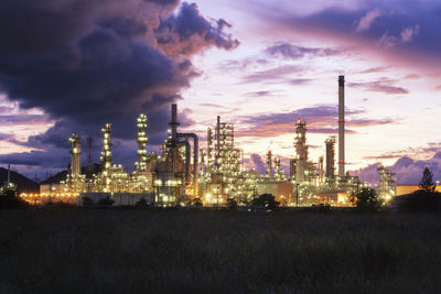 Illuminated factory against sky during sunset